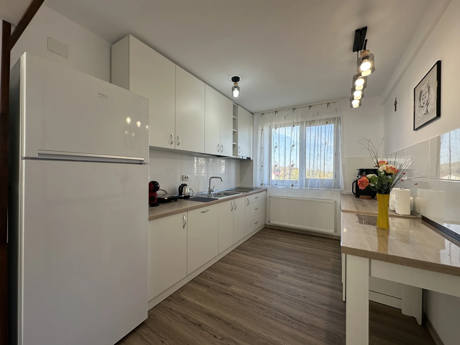 Bucătărie complet utilată, albă, cu frigider mare și blat lung, la Casa Tilă