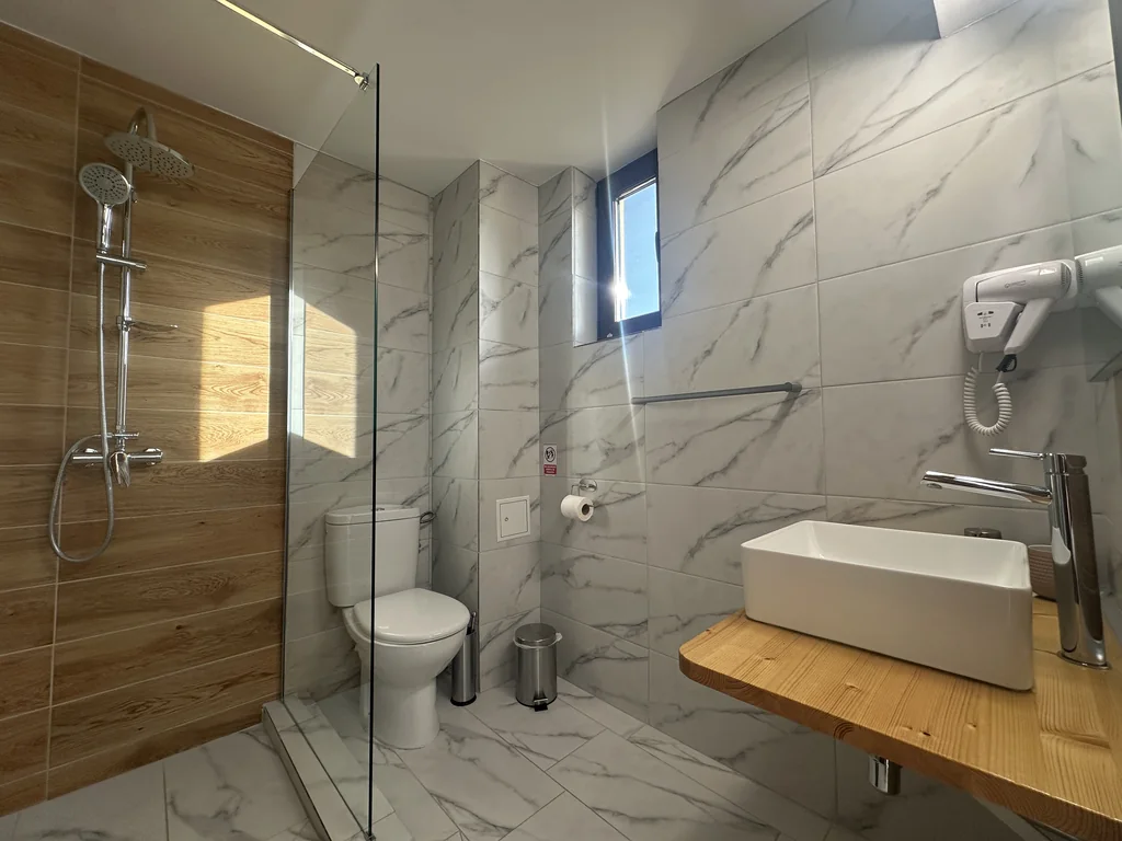 Baia camerei 105: marmură albă combinată cu lemn, duș walk-in
