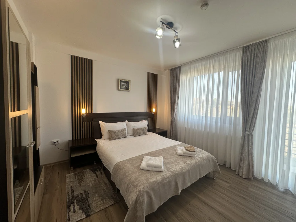 Camera 106 Casa Tilă: pat matrimonial, lumini ambientale și ferestre spre balcon