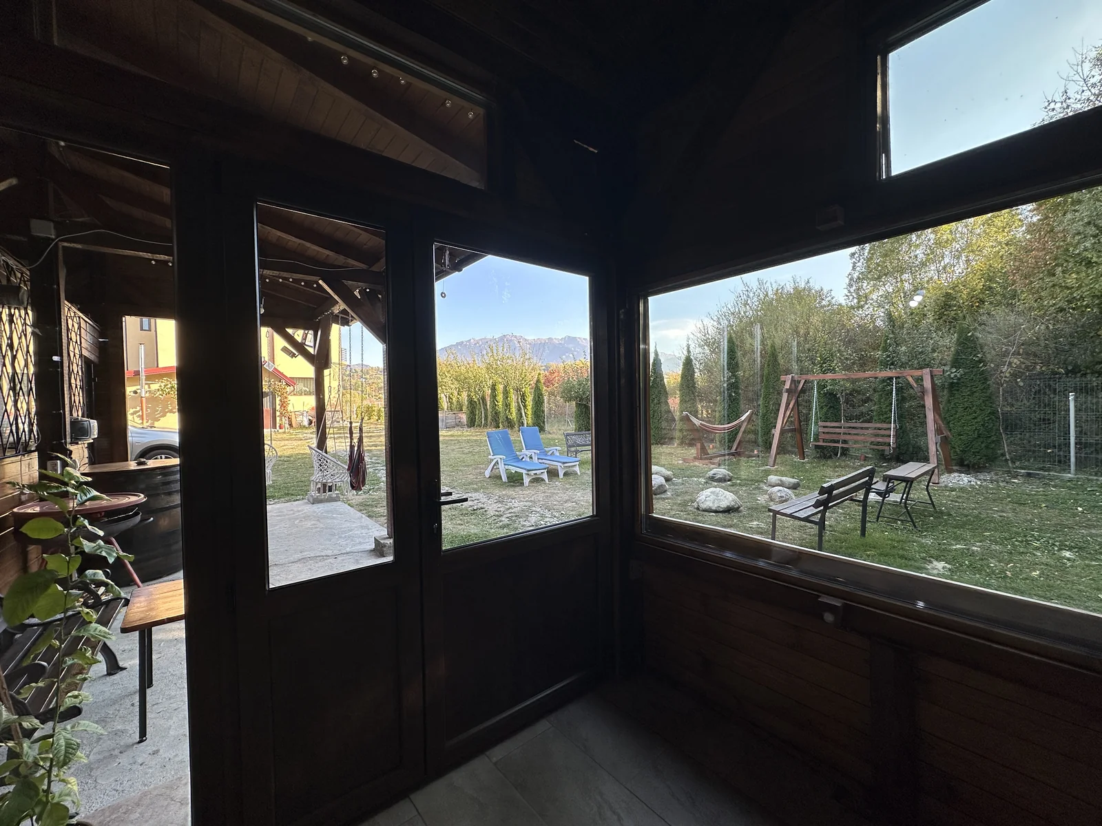 Vedere din foișor spre curte, leagăne, șezlonguri și munți